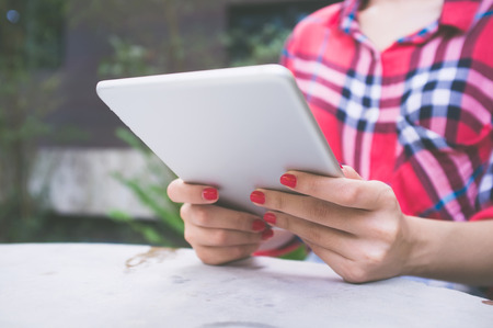 Close-up young woman using tablet in coffee shop. Vintage Filterの写真素材