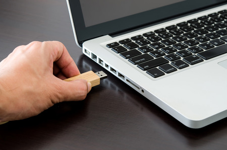 Hand inserting USB  flash drive into computer laptop.の写真素材