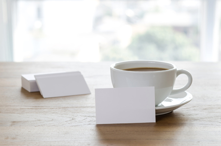 Blank business cards and cup of coffee on wooden table. Corporate stationary branding mock up.の写真素材