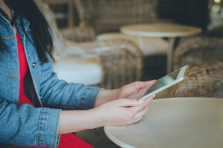 Close-up young woman using tablet with financial graph screen in coffee shop. Vintage Filterの写真素材
