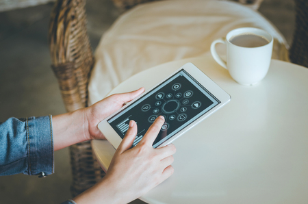 Close-up young woman using tablet with social icon screen in coffee shop. Vintage Filterの写真素材