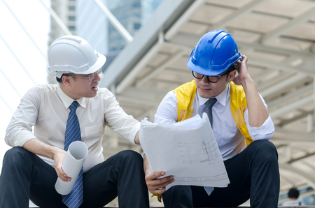 Two asian architects discussing about new project with paperwork at step of business walk way area in the city.の写真素材