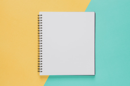 Office workplace minimal concept. Blank notebook on yellow and blue background. Top view with copy space, flat lay. Pastel color filter.の写真素材