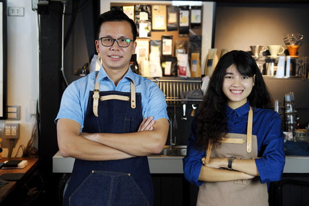 Portrait of smiling asian barista team with arms crossed at counter in coffee shop. Cafe restaurant service, Small business owner, food and drink industry concept.の写真素材