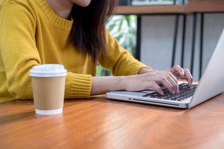 Online business concept. Close-up woman hand using computer laptop in coffee shop.