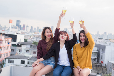 Youth friendship party concept. Group of asian friends drinking and having fun outdoor cheering at top roof.の写真素材
