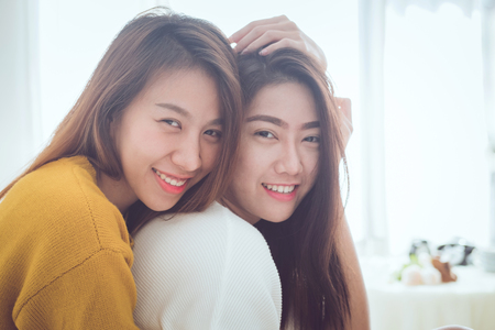 Lovely lesbian couple together concept. Couple of young asian women hugging in bed room with happiness moment.の写真素材