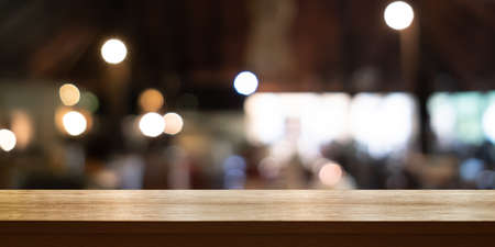 Empty wooden table top with blur coffee shop or restaurant interior background, Panoramic banner. Abstract background can be used for display or montage your products.の写真素材