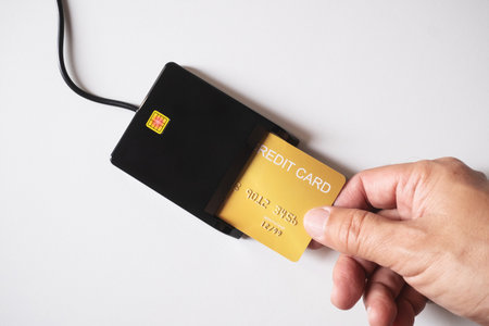 Hand swiping white credit card through payment terminal. Cashless technology and credit card payment concept, via internet for convenience of transaction.の写真素材
