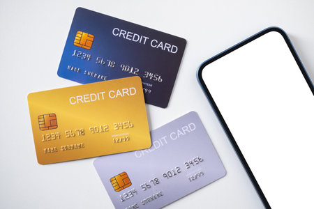 Pile of credit cards with smartphone on white background. Cashless technology and credit card payment concept, via internet for convenience of transaction.の写真素材
