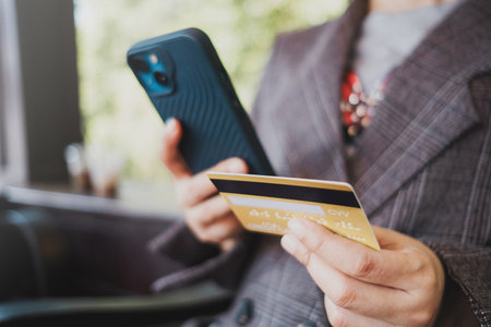 Close up female hands holding credit card and smartphone, shopping online, buying on internet,...