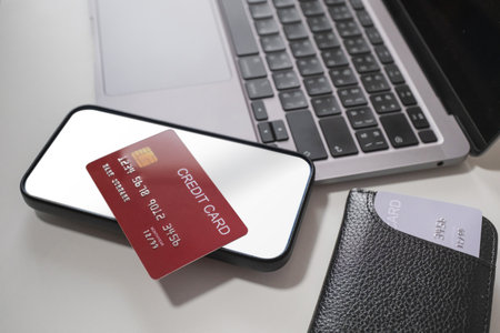 Credit card placed on smartphone and laptop on white background. Cashless technology and credit card...