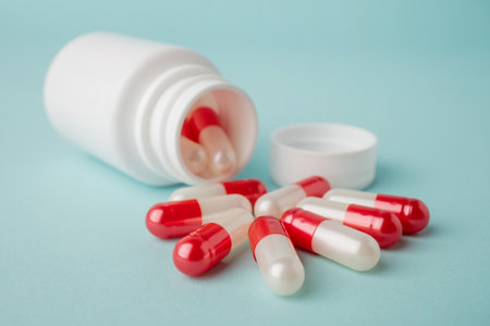 Close up bottle container with red and white medication capsules on blue background. Beauty,...