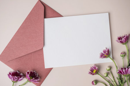 White blank greeting or invitation card and envelope with purple flower decoration on beige...