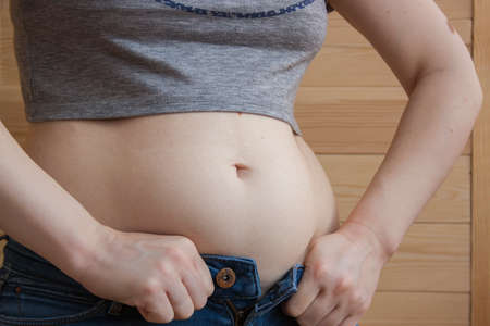 Overweight woman, hand holding excessive belly fat. Concept to reduce belly and shape up healthy...