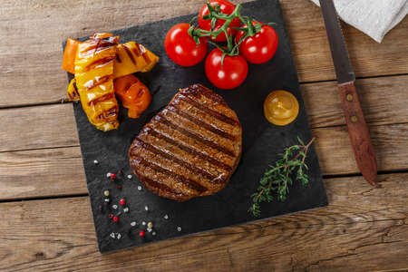 grilled beef steak with vegetables on a wooden surfaceの写真素材