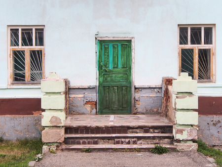 Destroyed brick porch, old green door and two windowの写真素材