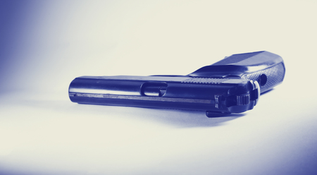 A dangerous weapon is on the table. Black silhouette on a white background. Cold weapon steel. A dangerous toy. Criminal intent. The flat trigger. A loaded gun. The preparation of the crime.の写真素材