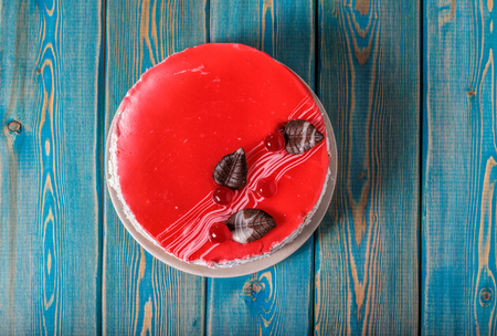 Cake with cherries. Bright red round cake. Decorated with cherry berries and leaves made of chocolate. A sweet dessert for tea and coffee.の写真素材