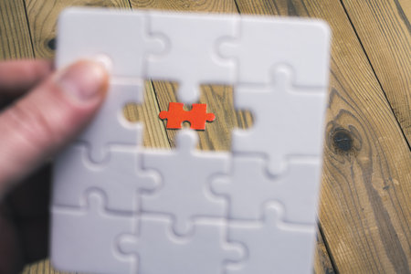A person is holding a puzzle piece with a red piece missing. Concept of missing something important...