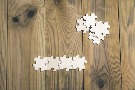 Puzzle pieces scattered across a wooden board. Business and corporate partnership concept.の写真素材