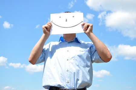 The young man covered his face with a sheet of paper with a pictureの写真素材
