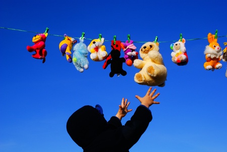 A little boy reaches for toys drying on a ropeの写真素材
