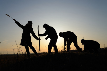 Four people silhouette against the setting sunの写真素材