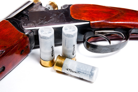 Hunting shotgun and ammunition on white background. Cartridges for hunting rifle. Close up view...