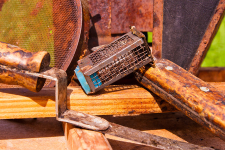 Vintage smoker and different kinds of beekeeper knifes, metal strainer, cage for bee queen on the wooden box. Close up view of cage for bee queen.の写真素材