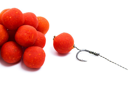 Close up view of fishing baits for carp. Accessories for carp fishing. View of fishing hook and several red boilies isolated on white background.の写真素材