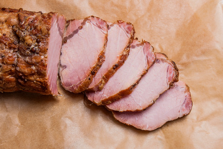 Close up view of sliced smoked with spice and herbs meat or ham on brown packing paper. Brown cloth on back background. Composition on light marble background.
の写真素材