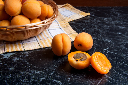 Ripe organic apricots in yellow wooden basket. Composition in rustic style - organic red juicy apricots in vintage wooden basket on dark marble background. Healthy food concept. Harvest time.
の写真素材
