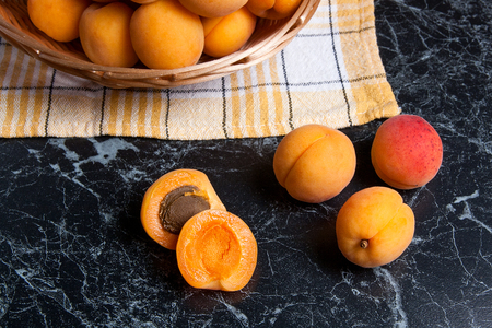 Ripe organic apricots in yellow wooden basket. Composition in rustic style - organic red juicy apricots in vintage wooden basket on dark marble background. Healthy food concept. Harvest time.
の写真素材