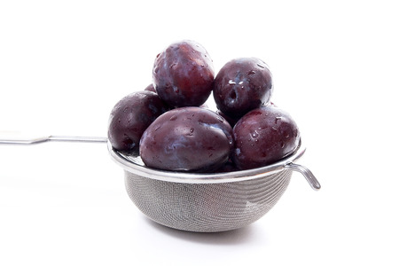 Steel colander with sweet juicy plums isolated on a white background.の写真素材