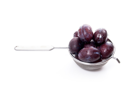 Steel colander with sweet juicy plums isolated on a white background.の写真素材