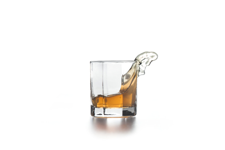 Whiskey splash out of glass, many drops of beverage get out from glass on light background.の写真素材