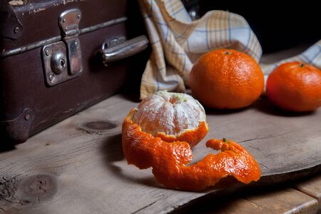 Several of whole fresh orange mandarine or oranges, tangerines, clementines, citrus fruits and one fruit is half peeled on wooden board
の写真素材