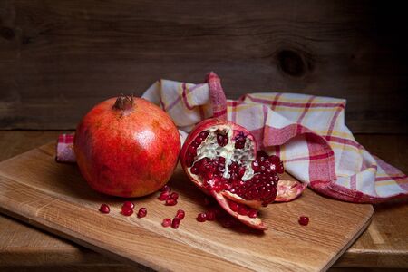 Composition of ripe red pomegranate and cracked pomegranate on a wooden background. Close up view of ruby seeds pomegranate fruit.の写真素材