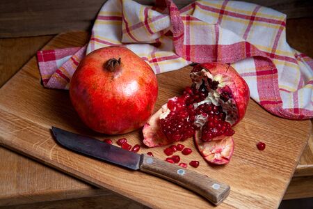 Composition of ripe red pomegranate and cracked pomegranate with vintage knife on a wooden background. Close up view of ruby seeds pomegranate fruit.
の写真素材
