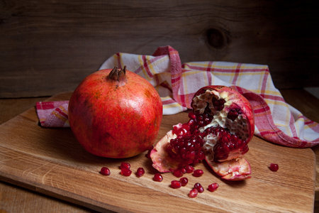 Composition of ripe red pomegranate and cracked pomegranate on a wooden background. Close up view of ruby seeds pomegranate fruit.の写真素材