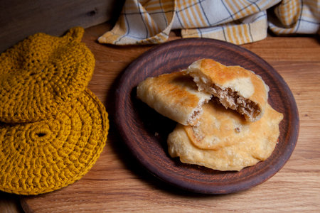 Clay plate with two of individual fried pies with meat on wooden table. Composition of fast food dinner - plate with two pies with pulled pork pastry on vintage wooden background.の写真素材