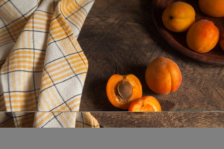Whole and half of apricot fruits with clay plate with fruits on background. Composition on vintage wooden background.の写真素材
