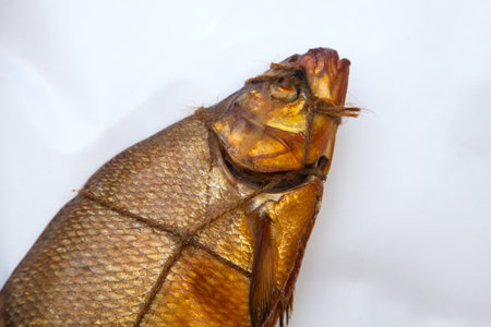 Appetizing smoked freshwater common breath fish in smokehouse. Beautiful delicious dried smoked fish with spices for home use on white paper.の写真素材