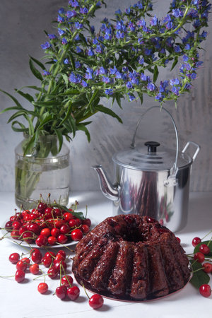 Composition on white background - delicious chocolate cake with sweet cherry, white plate with berry...