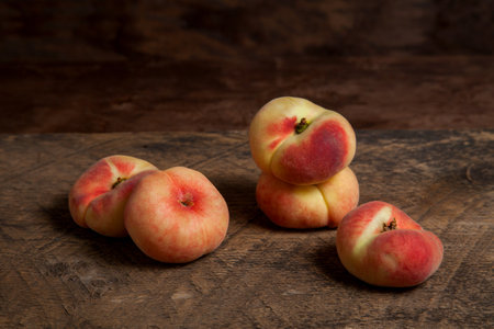 Several ripe chinese flat peach fruits or saturn peaches on vintage wooden background.の写真素材