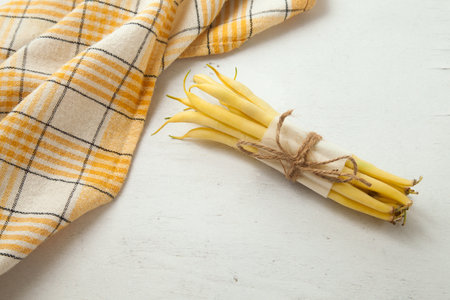 Bunch of raw yellow pods of haricot and yellow kitchen towel on wooden white background. French beans or Green beans also known as String beans from India. Vegetables collection.の写真素材