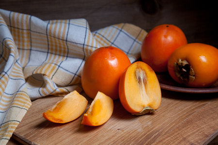 Composition of ripe delicious whole persimmon fruits, half and sliced fruit ready for eat on wooden background.の写真素材