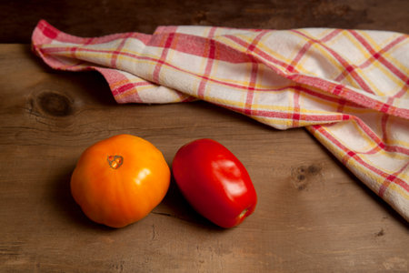 Whole ripe juicy red and yellow tomatoes on vintage wooden background with red towel. Vegetables collection.の写真素材