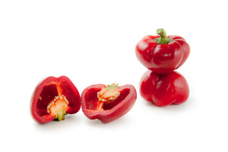 Two whole and halves of red bell pepper (capsicum) known as sweet bell pepper, paprika isolated on white background with clipping path.の写真素材